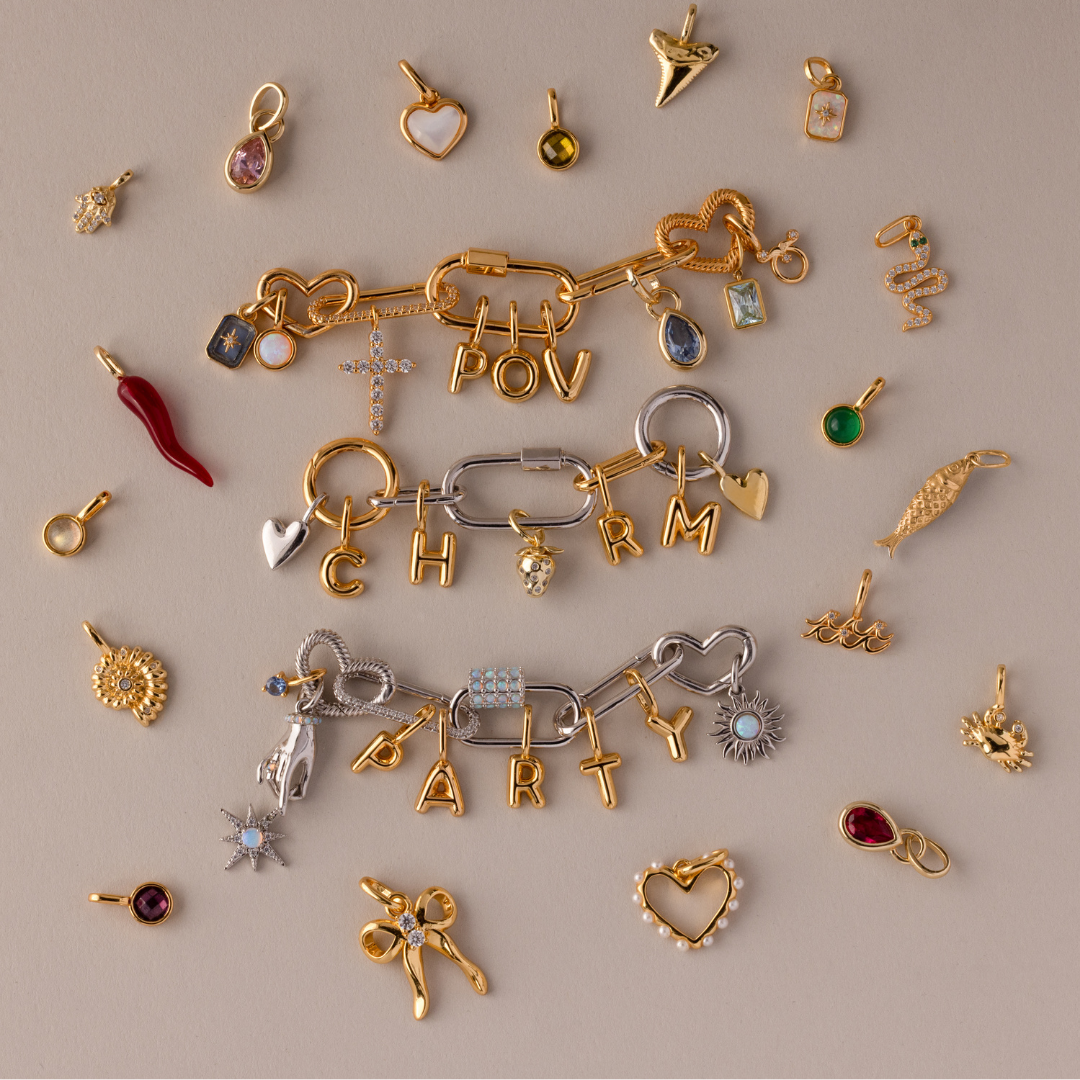 Various gold and gemstone charms, including a heart, star, butterfly, beetle, and other decorative shapes.