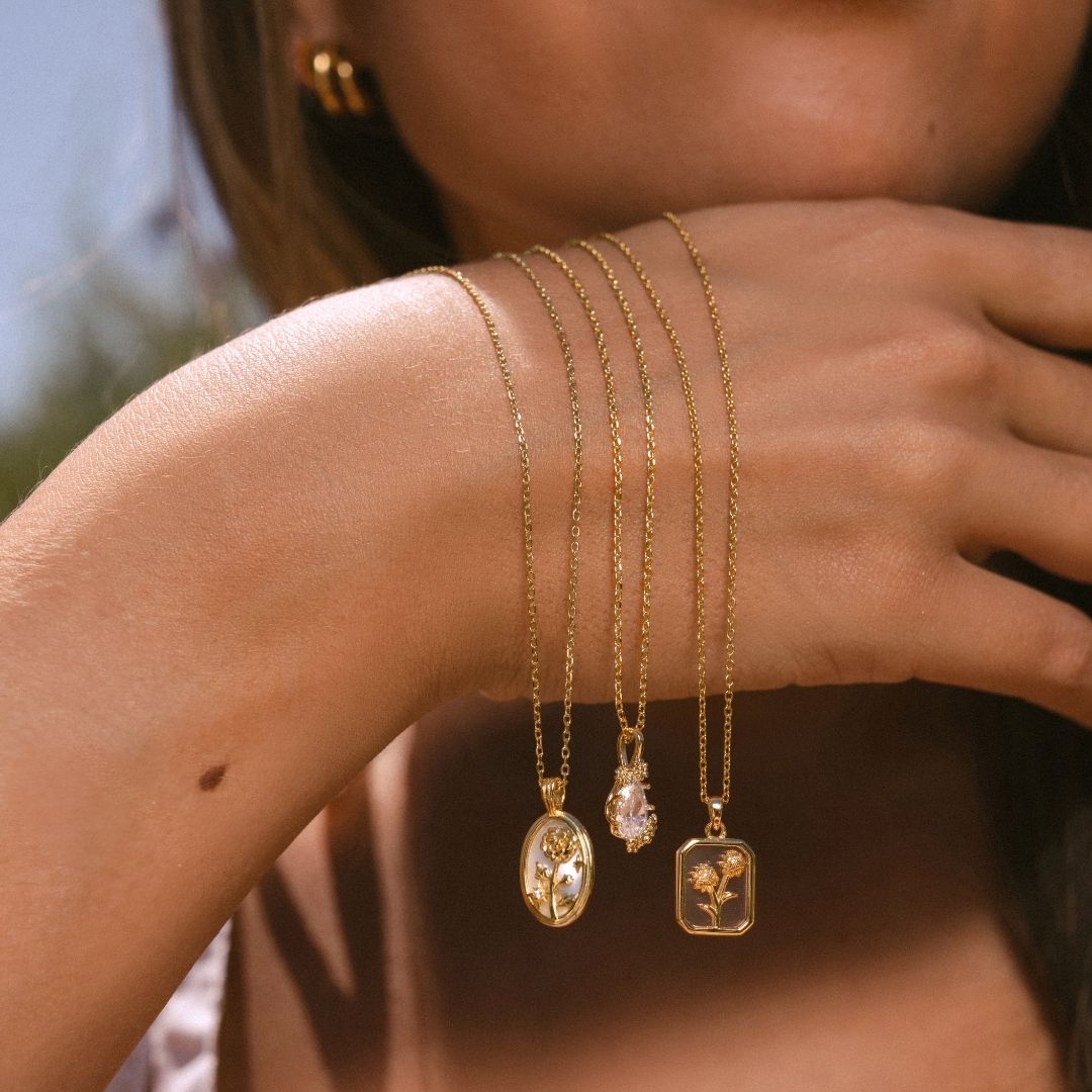 A close up of a female model wearing a jade beaded necklaces with a fish pendant necklace