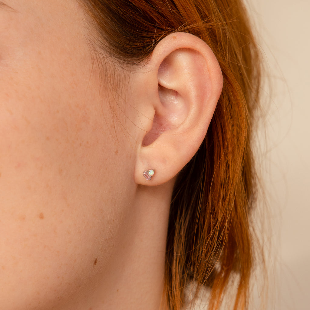 Close-up of a persons ear wearing Pink Baguette Opal Studs in Silver—perfect bridesmaid gifts—with auburn hair partly visible.