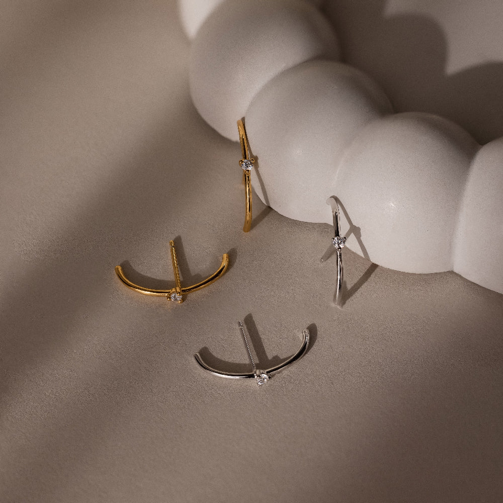 Gold and silver stud earrings on a neutral background