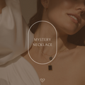 A woman in a white outfit wears two elegant necklaces. The text “Mystery Necklace” appears in an oval overlay, highlighting the allure of this refined jewelry piece.
