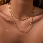 Close-up of a woman wearing two gold chains—a Bold Link Chain Necklace in 18K Gold (16) and a modern chain necklace (20).