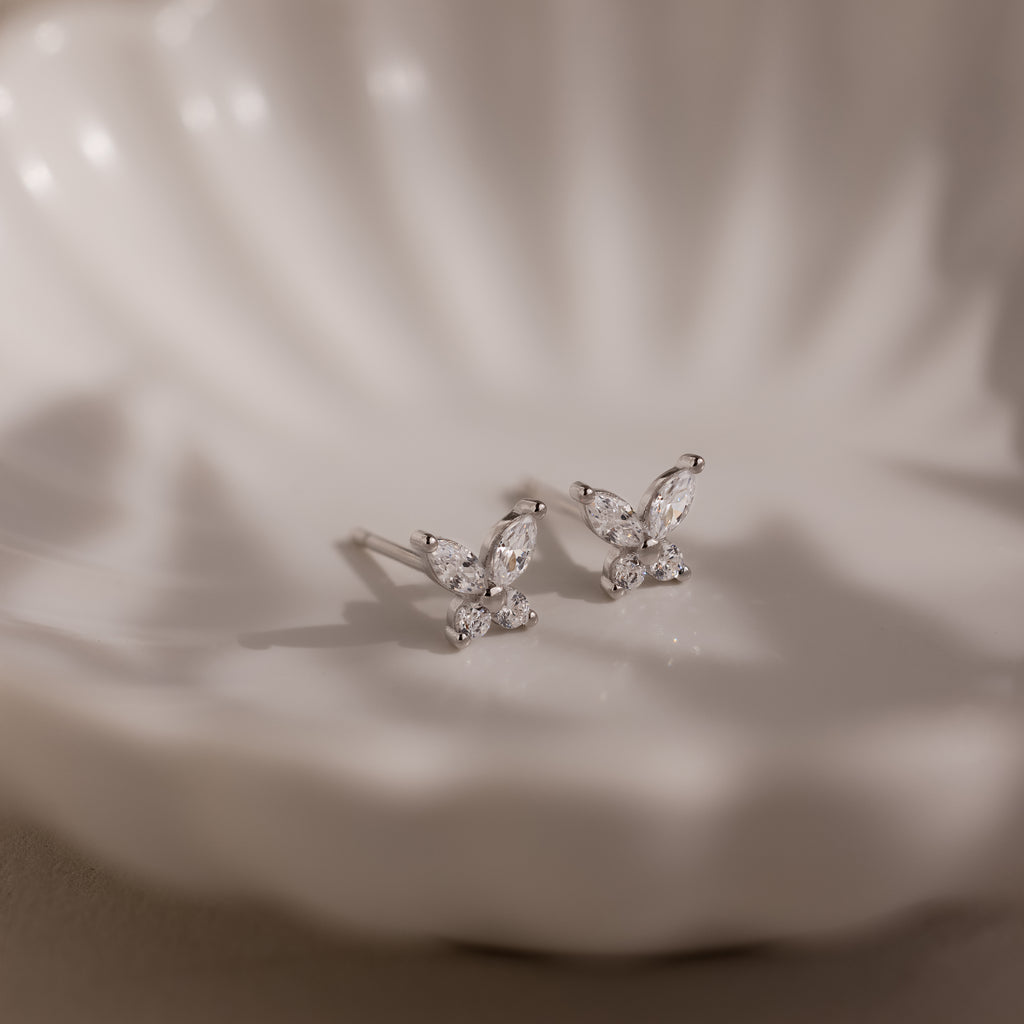 Silver butterfly-shaped earrings on a white jewelry dish