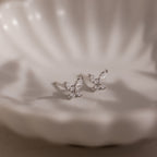 Silver butterfly-shaped earrings on a white jewelry dish