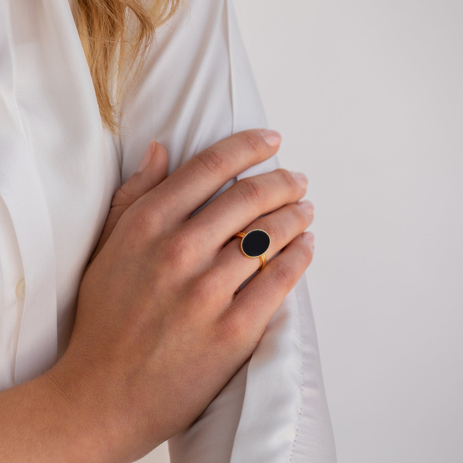 Close-up of a hand wearing the Midnight Hour Onyx Ring with an adjustable band, resting on a white long-sleeve shirt.