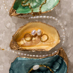 Gold-edged oyster shells display pearl jewelry, rings, and Twisted Pearl Hoops in 18K Gold, surrounded by ice and a pearl necklace.