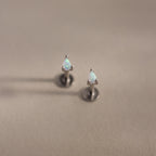 Teardrop opal flatback studs with silver prong settings on a soft beige surface.