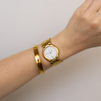 A Vintage Christian Bernard Honeycomb Gold Watch paired with a gold bracelet is worn on a wrist, shown against a plain light background.