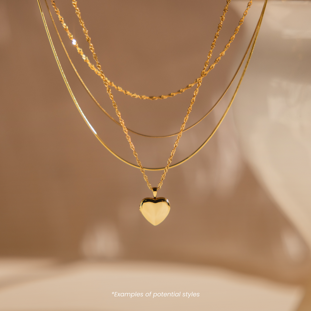 Mystery Jewelry features three layered gold necklaces, including one with a heart-shaped pendant, displayed on a neutral background to add whimsical charm to your collection.