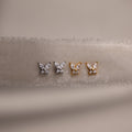 Gold and silver butterfly-shaped earrings on a beige fabric background