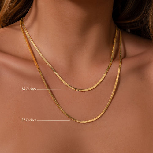 The Bold Snake Chain Necklace in 18K Gold, shown layered at 18 and 22 inches, highlights a modern jewelry look on a womans neck and collarbone.