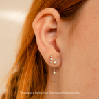 Close-up of an ear wearing three opal studs and a dangling opal earring in 18K gold—get inspired for your next pair with the Monthly Earrings Subscription Box.