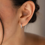 Close-up of an ear wearing our Classic Diamond Sprinkle Huggie earring with a neutral background