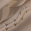 Two floral chain necklaces in gold and silver on a beige fabric background