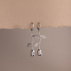 Silver earrings shaped like roses on a beige background