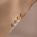 Two pairs of gold and silver diamond earrings on a beige fabric surface