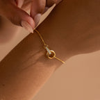 The Interlocking Opal Inlay Necklace and Bracelet Set in 18K Gold features delicate pieces with opal accents, elegantly displayed on a wrist and neck against a neutral background.