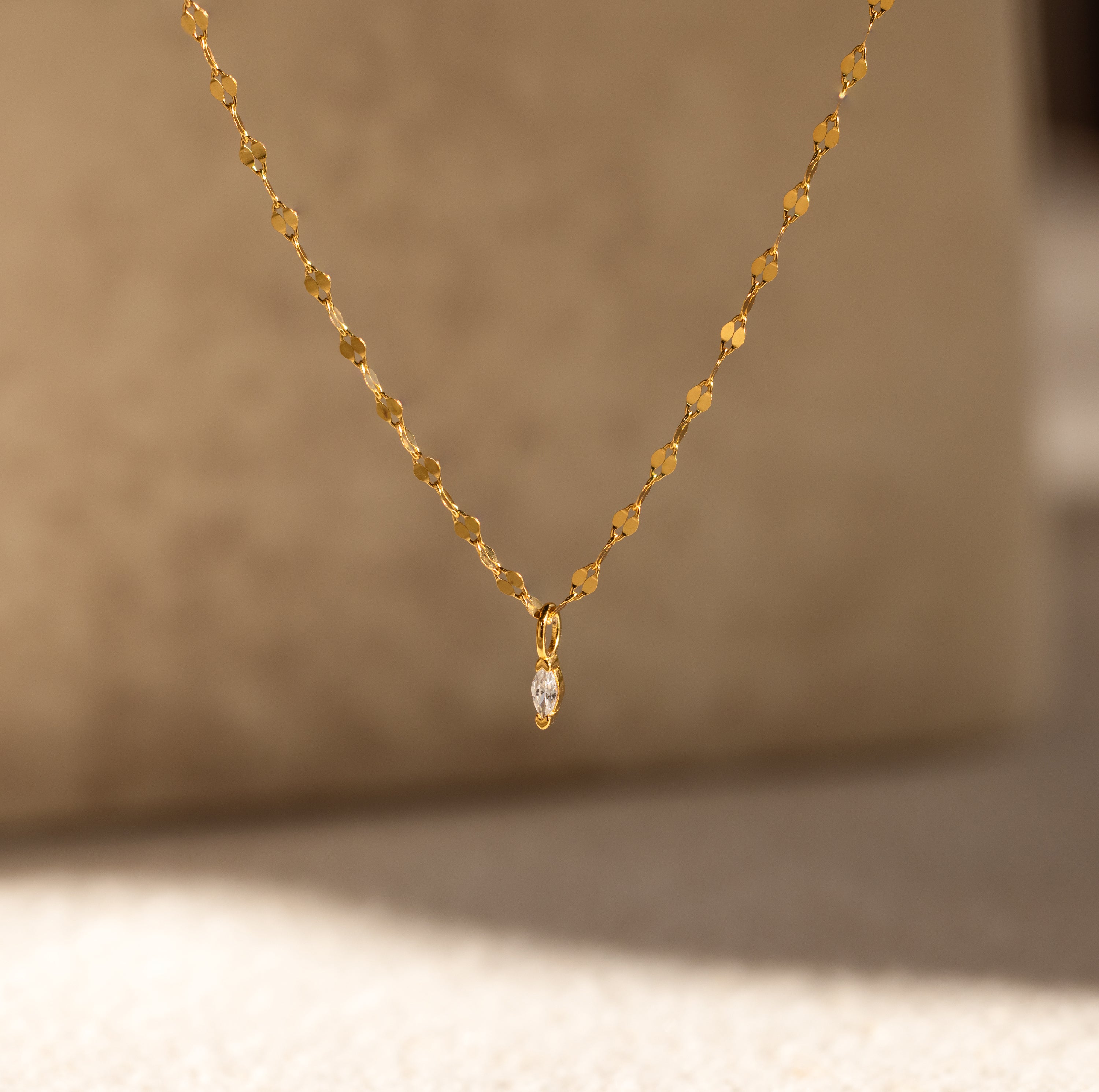 The Dainty Marquise Pendant Necklace features a delicate mirror twist chain and a small marquise-cut diamond teardrop, shown against a soft, neutral background.