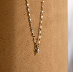 Dainty Marquise Pendant Necklace in Silver with a mirror twist chain, displayed elegantly against a speckled, light brown cylindrical surface.