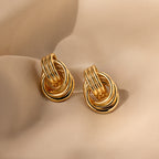 Triple Knot Earrings in 18K Gold feature interlocking gold hoops and are elegantly displayed on soft beige fabric—making them a perfect anniversary gift.