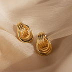 Triple Knot Earrings with interlocking circles, shown on soft beige fabric under gentle lighting—an elegant choice and perfect anniversary gift.