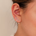 Close-up of an ear with multiple piercings, each adorned with the Diamond Earrings Set in Sterling Silver, featuring sparkling huggie hoops and dainty studs.