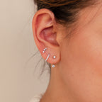 Close-up of an ear with the Diamond Earrings Set, featuring five sparkling pieces—delicate pavé huggie hoops and an ear climber—arranged along the earlobe and cartilage.