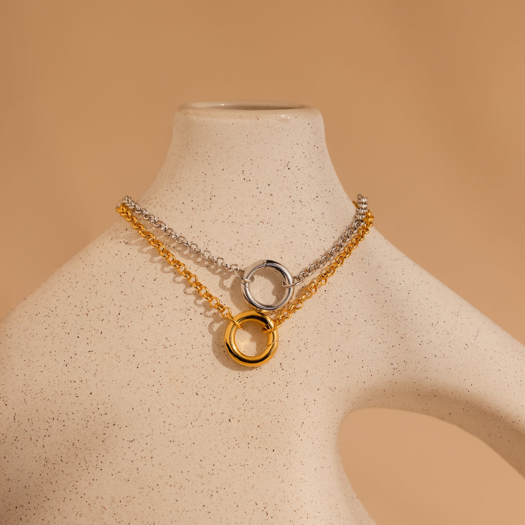 The Rolo Circle Charm Bracelet, featuring a circular pendant with a detachable hinged circle, is displayed on a speckled beige mannequin bust.