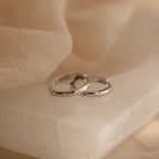 Classic Diamond Sprinkle Huggies rresting on a beige stone slab with soft draped fabric in the background.
