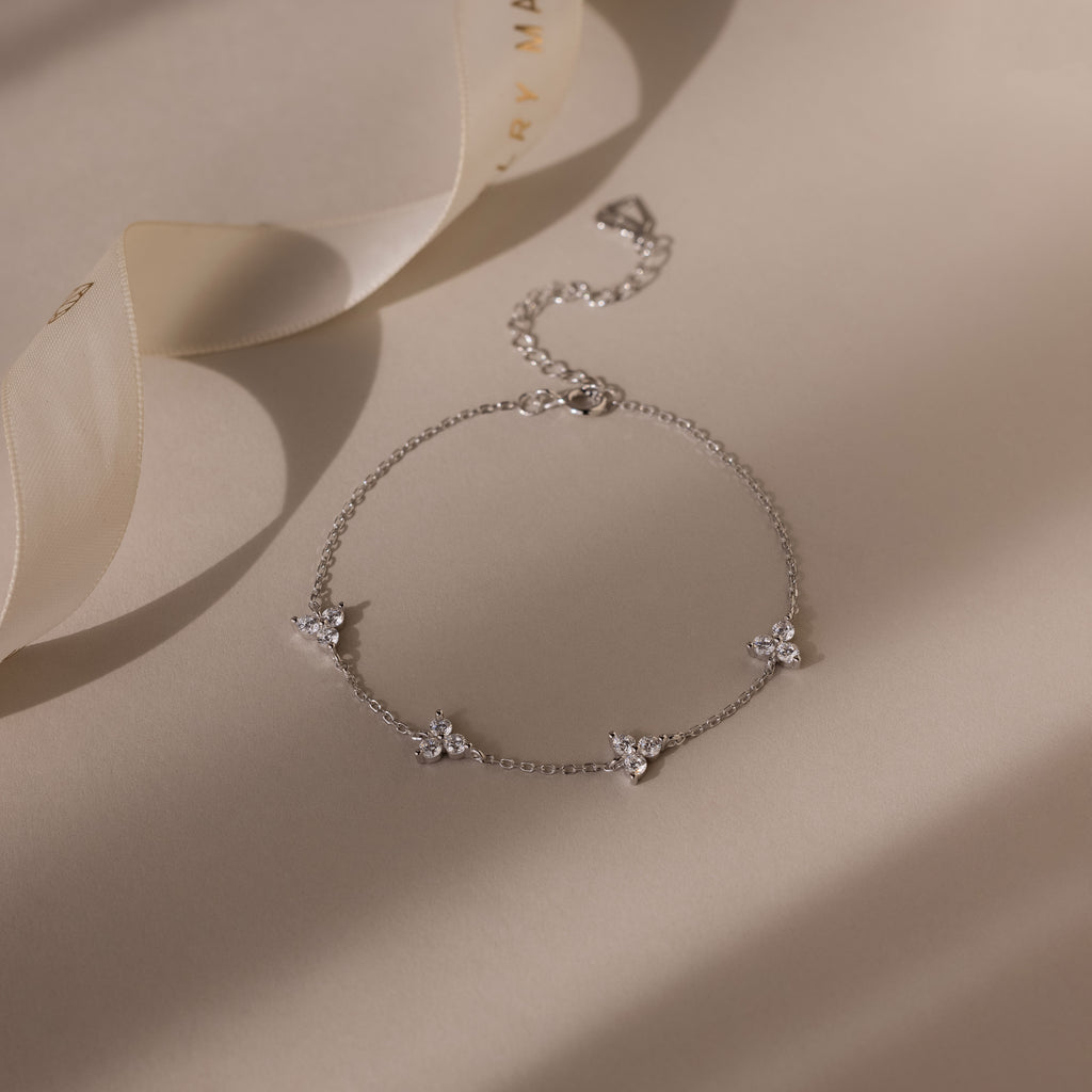 Silver bracelet with floral charms on a beige fabric background