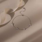 Silver bracelet with floral charms on a beige fabric background