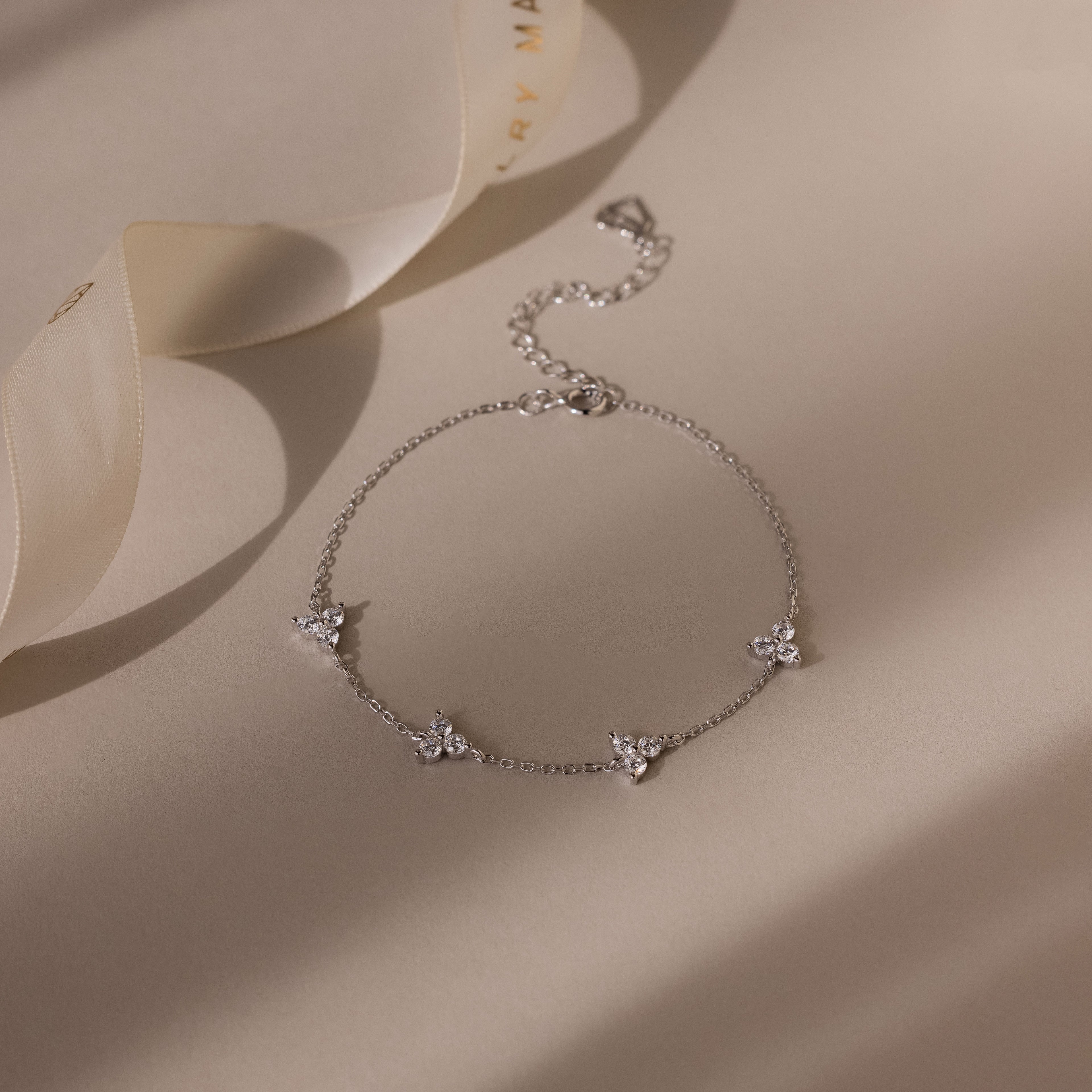 Silver bracelet with floral charms on a beige fabric background