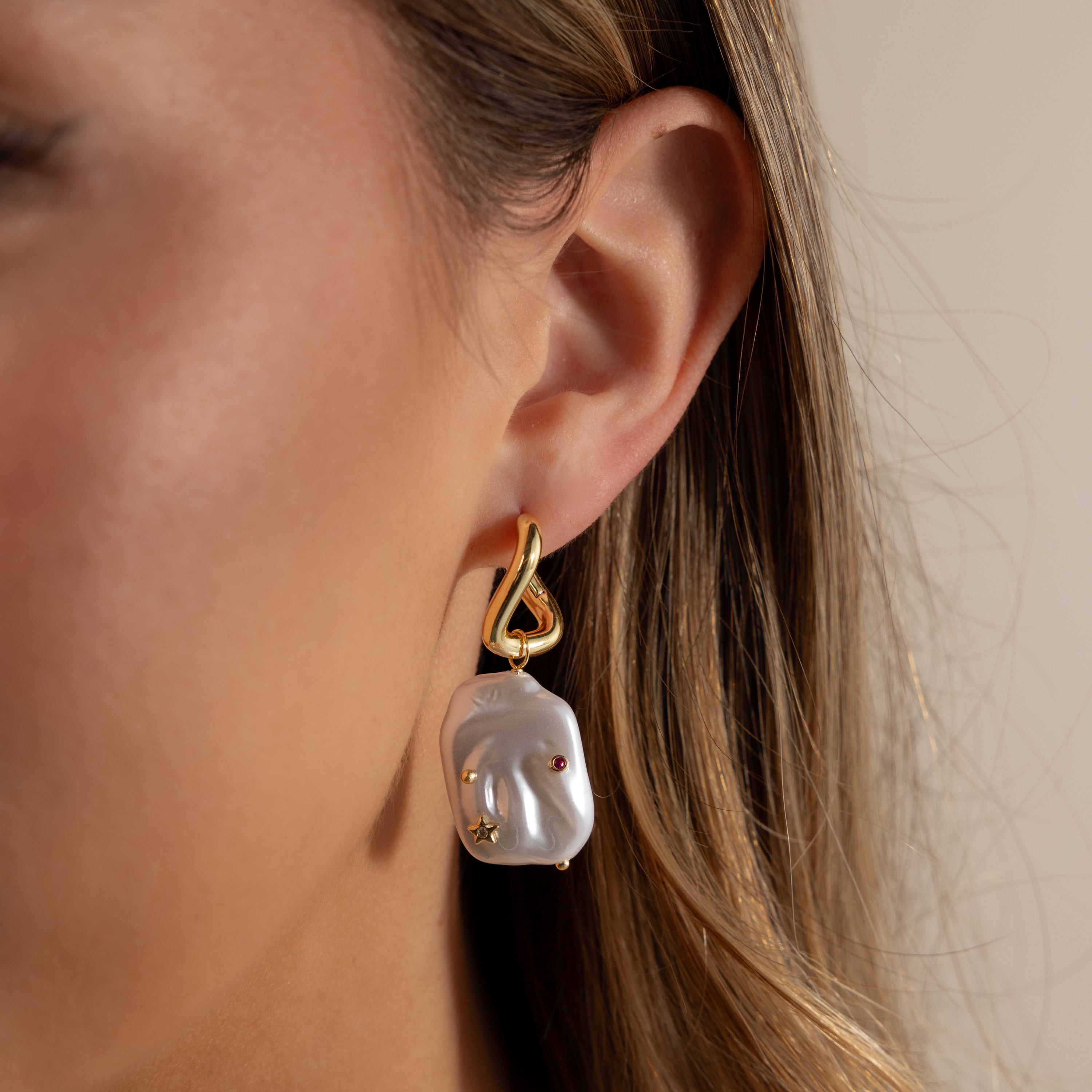 Close-up of a woman's ear wearing Celestial Baroque Pearl Charm Hoops in 18K Gold, featuring a unique pearl and gemstone design—perfect for lovers of elegant, distinctive jewelry.