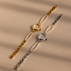 Two Beaded Pearl Timepiece watches, one in gold and one in silver, are showcased on a beige background. Each watch exudes the timeless charm of vintage elegance.