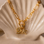 The Pave Dome Charm adds sparkle to your jewelry stack, shown here on a gold chain necklace and displayed on a cream-colored ceramic shell.