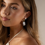 Woman with long hair wearing a halter top and elegant Celestial Baroque Pearl Charm Hoops in 18K Gold, looking slightly to the side.