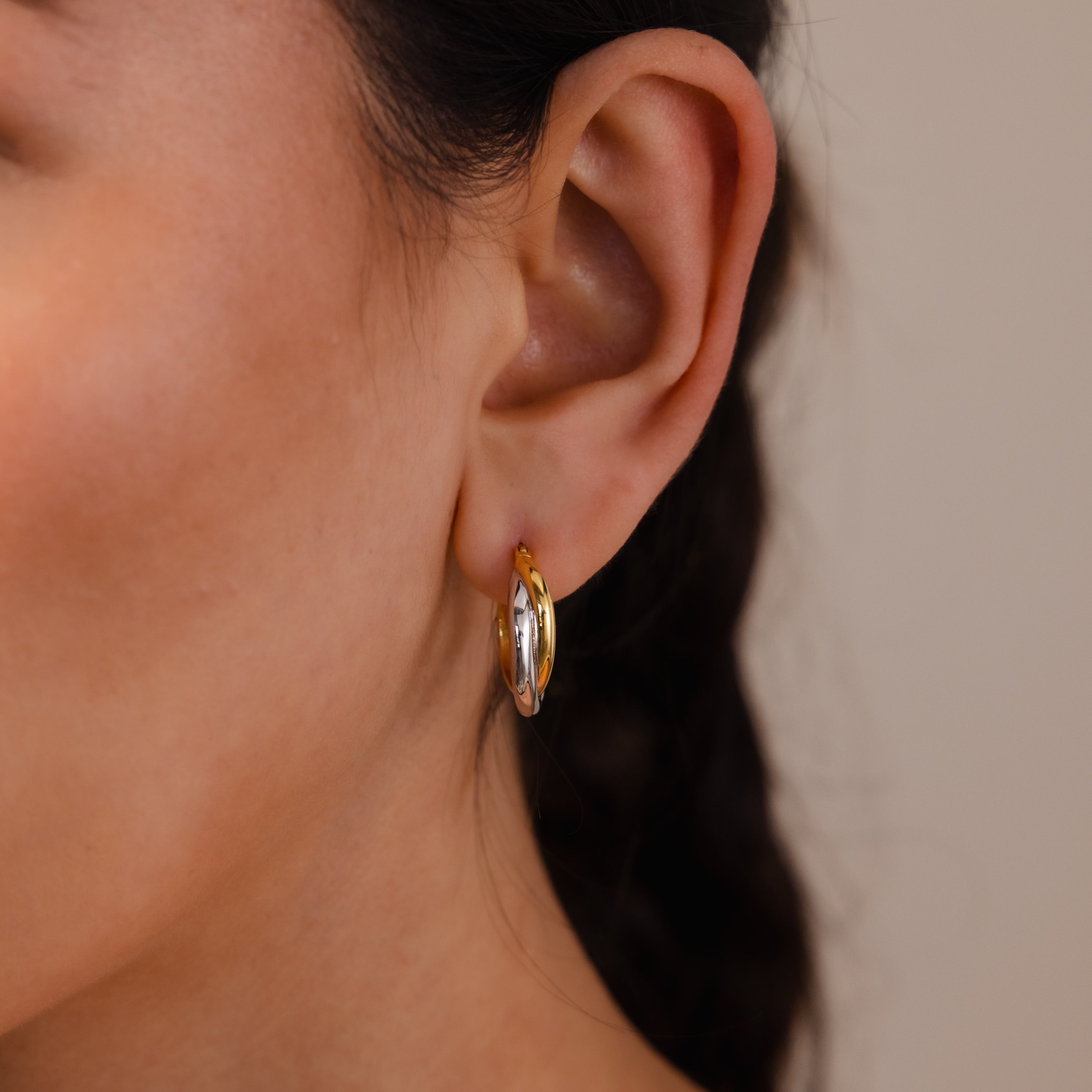 Close-up of a woman's ear wearing Twisted Mixed Metal Hoops, showcasing their elegant two-tone gold and silver design for a modern, stylish look.