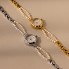 Two Beaded Pearl Timepieces, featuring elegant pearl and chain bands in gold and silver, are displayed on a beige background.