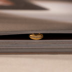 The Pave Dome Charm in 18K Gold adds sparkle as it rests between the pages of a closed book.