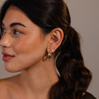 Woman with long dark hair in a ponytail wears Twisted Mixed Metal Hoops, looking to the left.