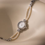 Beaded Pearl Timepiece in Sterling Silver displayed on a smooth, cream-colored curved surface.