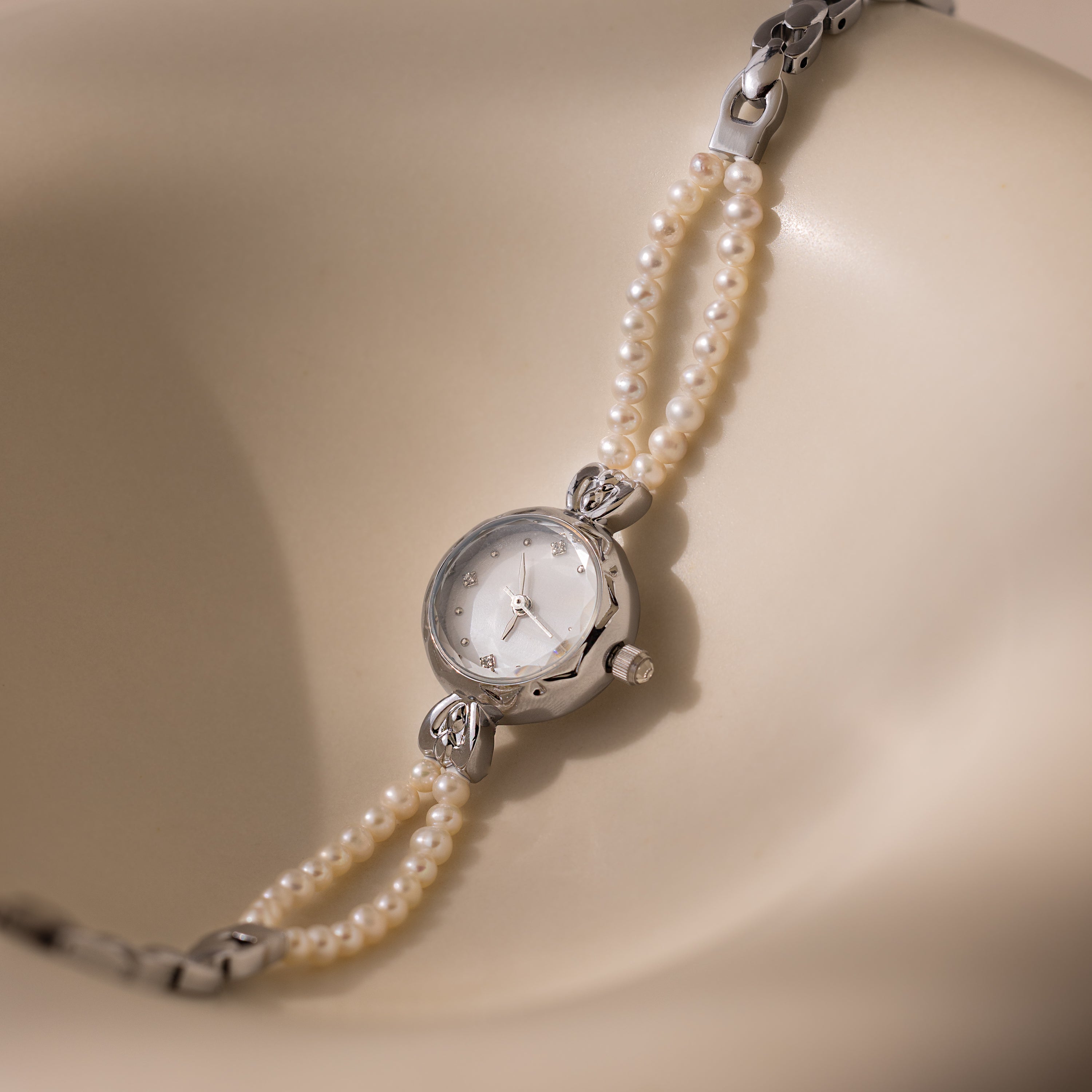 Beaded Pearl Timepiece in Sterling Silver displayed on a smooth, cream-colored curved surface.