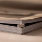A Pave Dome Charm in Silver gleams in the crease of an open book, its shine beautifully framed by pages folded into a heart shape.
