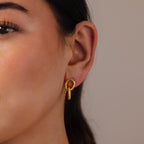 Close-up of a woman's ear wearing Twisted Link Earrings in 18K Gold—modern hoops with a textured, vertical design—for an elegant jewelry statement.