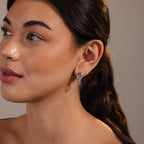 A woman with long dark hair wears Twisted Link Earrings in White Gold, gazing to the side against a neutral background.