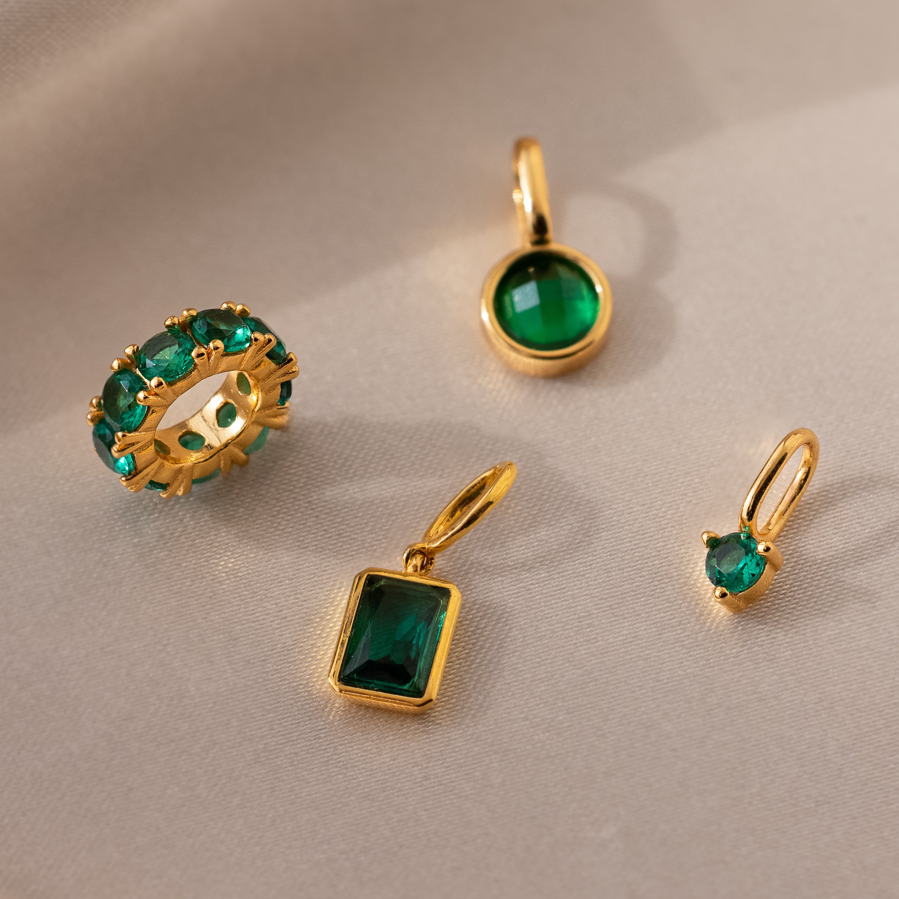 Several emerald colored charms in different shapes set next to each other