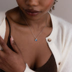 Model wears silver cable chain with aquamarine pear birthstone charm and blue zircon baguette birthstone charm