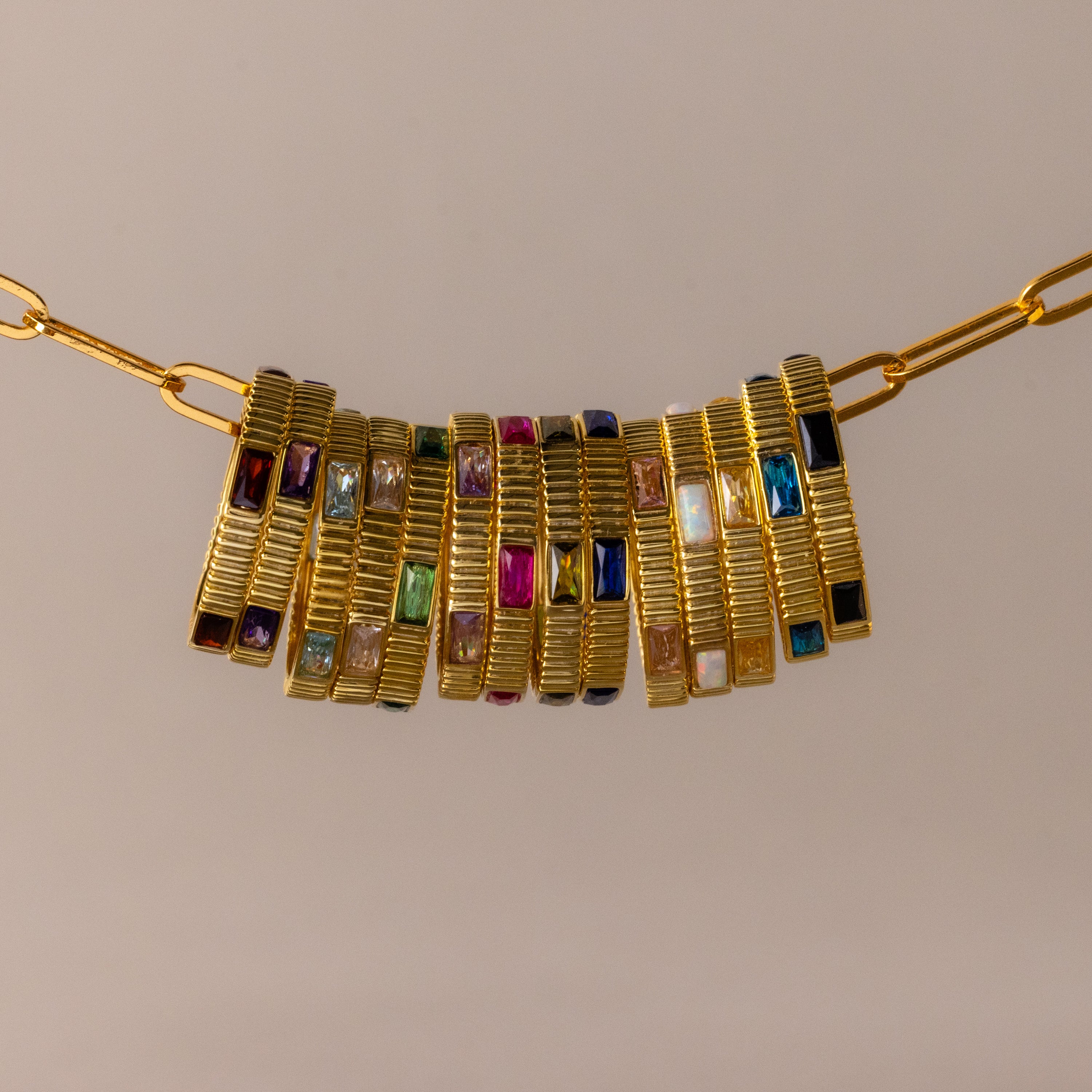 The Ribbed Baguette Birthstone Eternity Ring features rectangular multicolored stones set in ribbed gold, displayed against a neutral background.