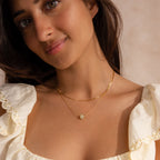 Model wearing a delicate gold chain necklace featuring a single round green jade bead, layered with a dainty box chain necklace.