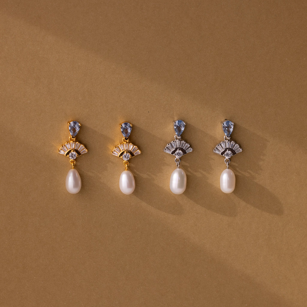 Four pairs of Aquamarine Pearl Drop Earrings—two gold, two silver—capture vintage glamour with pearls on a brown background. Timeless and elegant, perfect as wedding earrings.